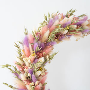 Close-up van flowerhoop van paarse, groene en roze droogbloemen, luchtig bevestigd op een zwarte metalen ring