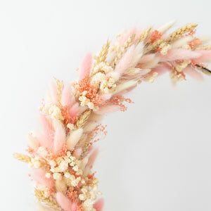 Detail van hangende flowerhoop met droogbloemen in roze en crème kleuren op een zwarte metalen ring van 30 cm