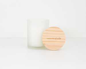 Geurkaars in een frosted glas met de tekst 'warmte en licht' gegraveerd op het houten deksel 